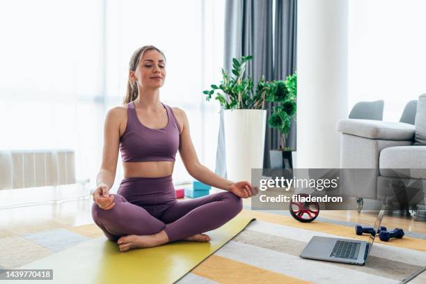 sporty woman exercising at home - lotus position imagens e fotografias de stock