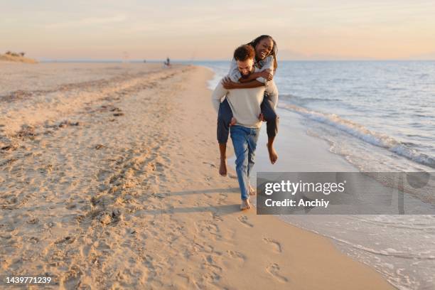 couple enjoying a day at the beach - romantic couple walking winter beach stock pictures, royalty-free photos & images