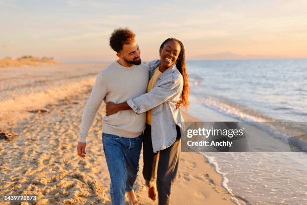 paar spazieren am strand während des sonnenuntergangs - beach couple stock-fotos und bilder