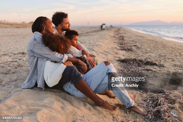 happy multiracial parents enjoying sunset with their children at beach - grand 8 stock pictures, royalty-free photos & images