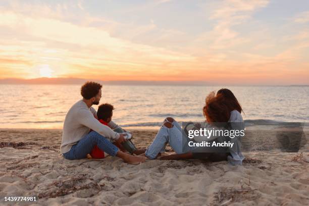 happy multiracial parents enjoying sunset with their children at beach - adventure sunset stock pictures, royalty-free photos & images