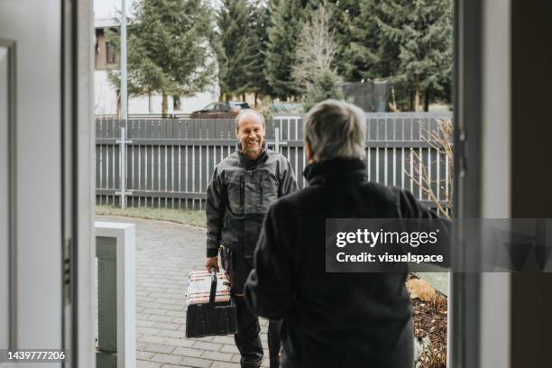 electrician talking to a customer on the porch of the house - tradesman toolkit stock pictures, royalty-free photos & images