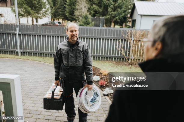 electrician talking to a customer on the porch of the house - elektricien stockfoto's en -beelden