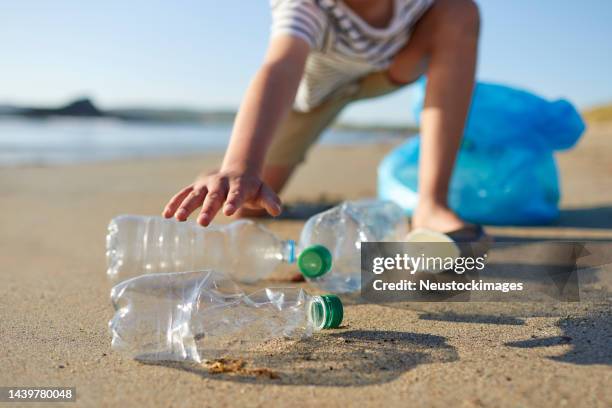 boy picking up empty plastic waste on sunny day - clear plastic cup stock pictures, royalty-free photos & images