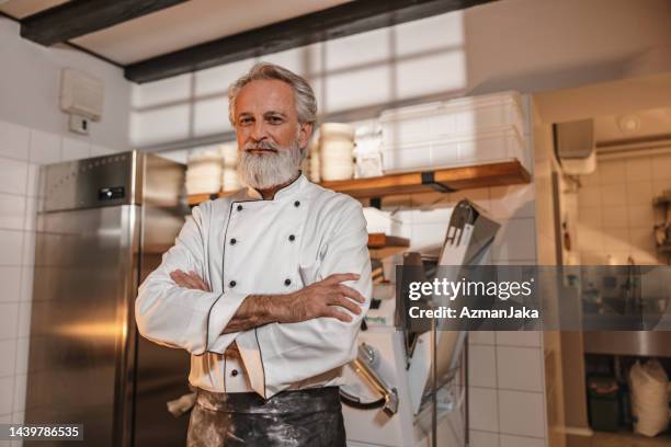 caucasian baker with arms crossed standing in the kitchen of the bakery - baker smelling bread stock pictures, royalty-free photos & images