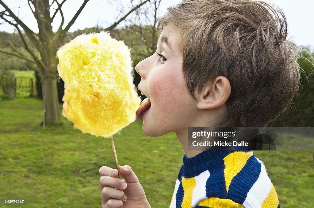 A child licking a giant yellow cotton candy