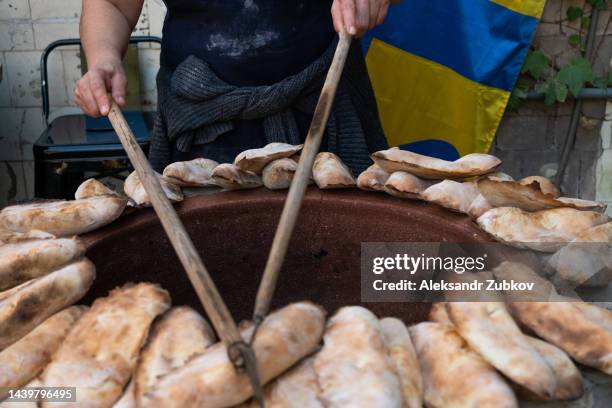 a georgian woman baker bakes tortillas in a tandoor. the process of making and baking bread in a traditional georgian tandoor. home national bakery, outdoors, on a city street. retail trade. a simple life, not an urban scene. a trader in the market. - savannah georgia 個照片及圖片檔