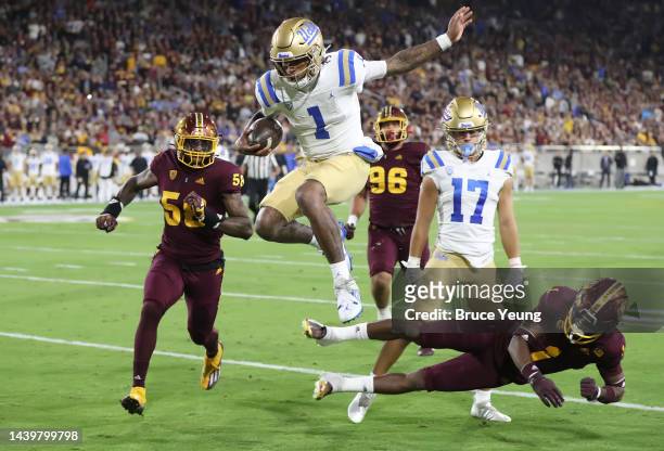 Dorian Thompson-Robinson of the UCLA Bruins leaps over Jordan Clark of the Arizona State Sun Devils for a touchdown in the first quarter of the game...