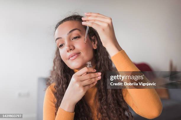 young satisfied woman using face oil in her daily skin routine - face oil stock pictures, royalty-free photos & images