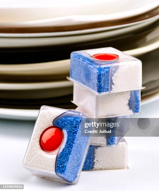 group of bars of soap for dishwashers. at the bottom stack of plates - vaatwastablet stockfoto's en -beelden