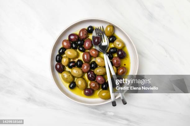 mixed green olives and black olives with olive oil top view - khaki green stock pictures, royalty-free photos & images