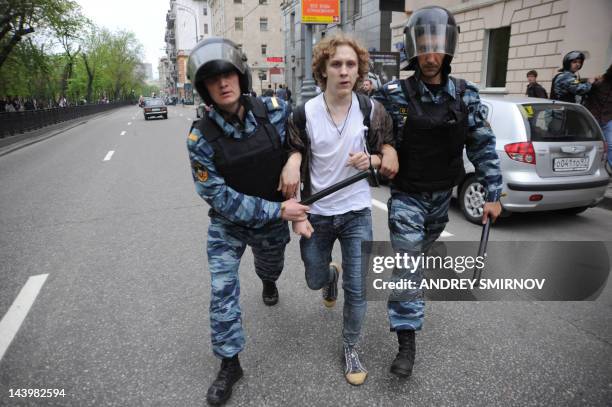 Riot police, officers escort an anti-Putin protester wearing white ribbons, who was detained at the Tverskoi Boulevard in central Moscow, on May 7,...