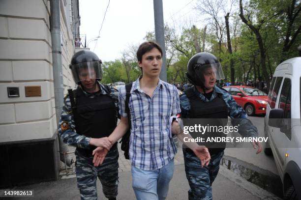 Riot police, officers escort an anti-Putin protester wearing white ribbons, who was detained at the Tverskoi Boulevard in central Moscow, on May 7,...
