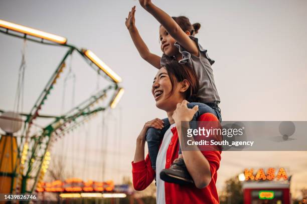 mom and daughter in amusement park - theme park imagens e fotografias de stock