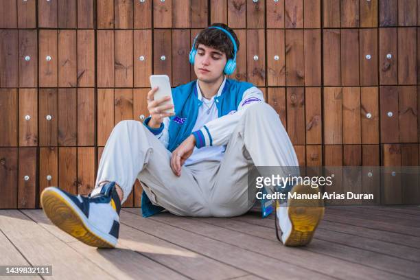 full body image of a handsome young man enjoying the weather in the city, relaxing while listening to his favorite music from wireless headphones. - headphone man on neck stockfoto's en -beelden