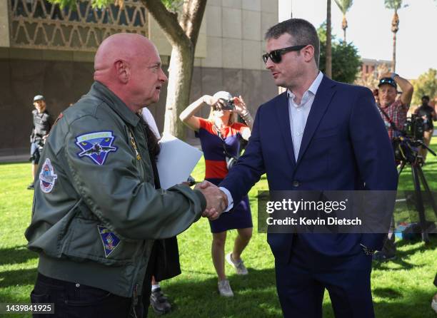 Sen. Mark Kelly shakes hands with Jack McCain, son of the late Arizona Republican Senator John McCain, at a press conference outside the Arizona...