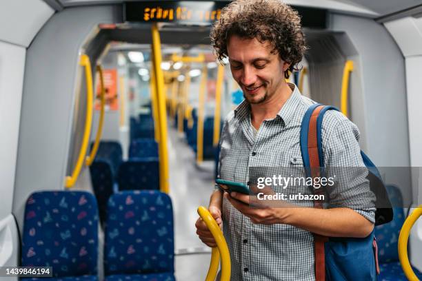 young man using phone in a subway train in stockholm - stockholm metro stock pictures, royalty-free photos & images