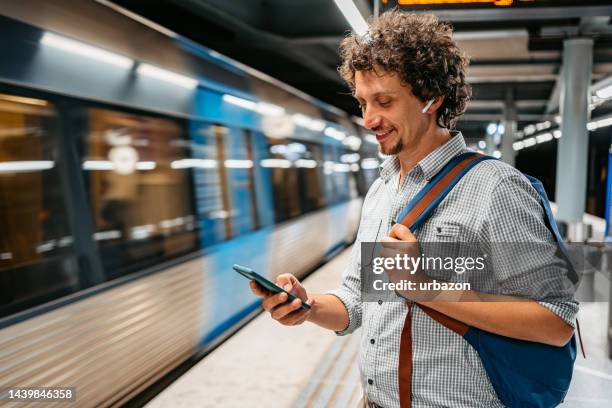 ストックホルムで地下鉄の電車を待っている間に電話を使う若い男 - 地下鉄電車 ストックフォトと画像