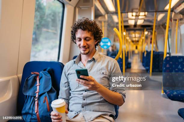 young man using phone in a subway train in stockholm - underground rail stockfoto's en -beelden