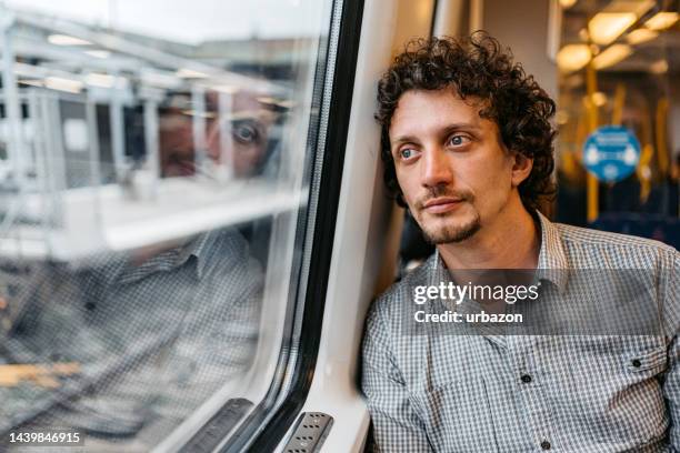 young man leaning on a window of a subway train in stockholm - reflection in train window stock pictures, royalty-free photos & images