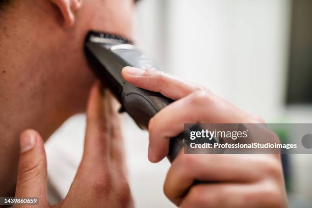 una foto en primer plano de un joven haciendo su rutina matutina y afeitándose. - maquinilla de afeitar fotografías e imágenes de stock