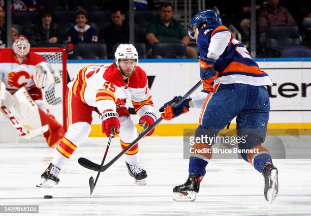 Noah Hanifin of the Calgary Flames defends against Oliver Wahlstrom of the New York Islanders during the first period at the UBS Arena on November...