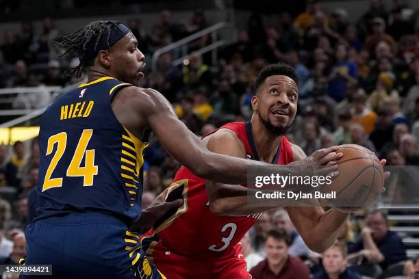 McCollum of the New Orleans Pelicans dribbles the ball while being guarded by Buddy Hield of the Indiana Pacers in the fourth quarter of the game at...