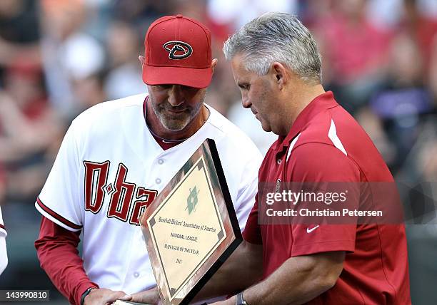 Manager Kirk Gibson of the Arizona Diamondbacks receives the NL Manager of the Year Award from GM Kevin Towers before the Opening Day game against...
