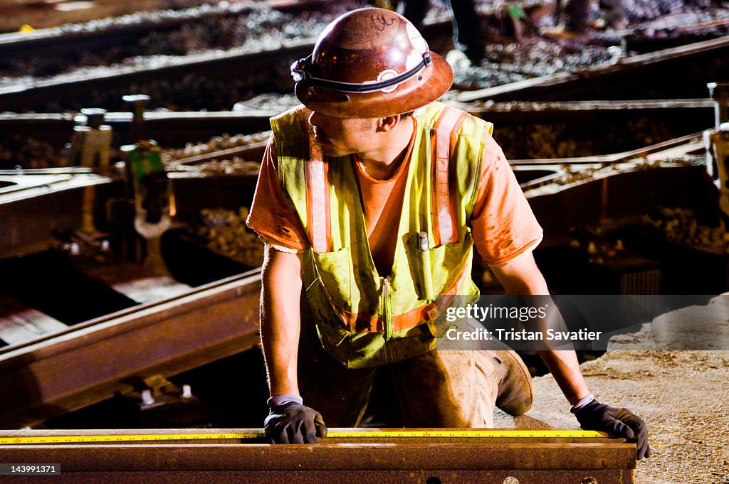 Worker measuring rail with tape