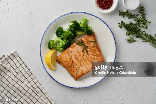 paleo, keto, lshf, fodmap or dash diet. baked fish and vegetables. grilled fried salmon, broccoli, mediterranean food with steamed fish. oven dish, healthy concept, gluten free, clean eating, balanced food. white ceramic plate on gray table. top view - zalm gerecht stockfoto's en -beelden