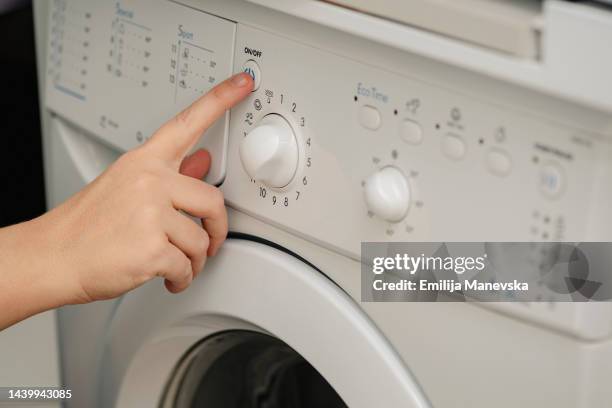 hand of person adjusting washing machine knob - hand wasser stockfoto's en -beelden