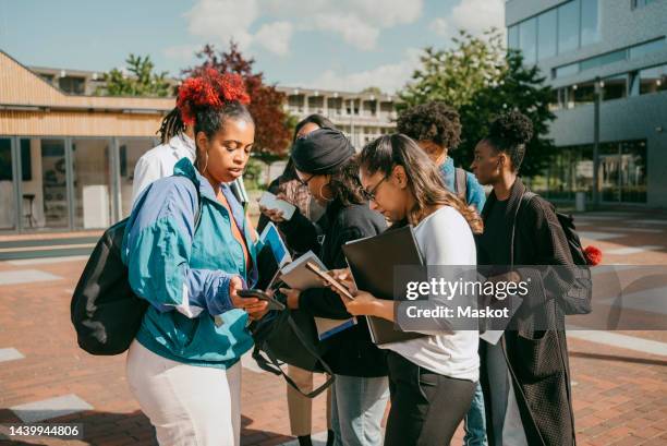 multiracial male and female students with teachers discussing while standing in college campus - discussion germany outdoor friends stock-fotos und bilder