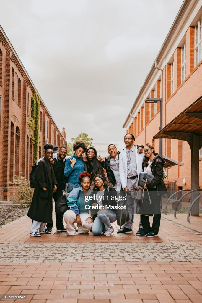 Multiracial group of teachers and students posing together in university campus