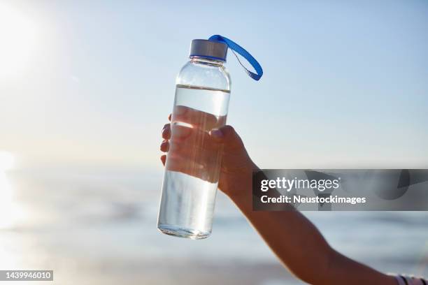 clean drinking water in glass bottle held by boy - reusable water bottle beach stock pictures, royalty-free photos & images