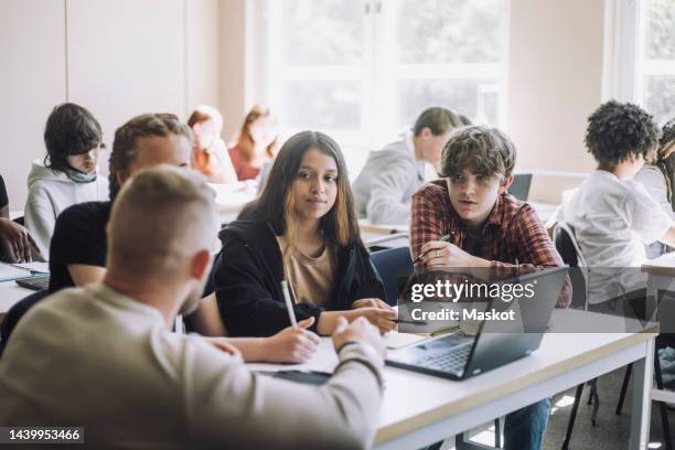 professor explaining male and female students e-learning through laptop in classroom - pedagoga imagens e fotografias de stock