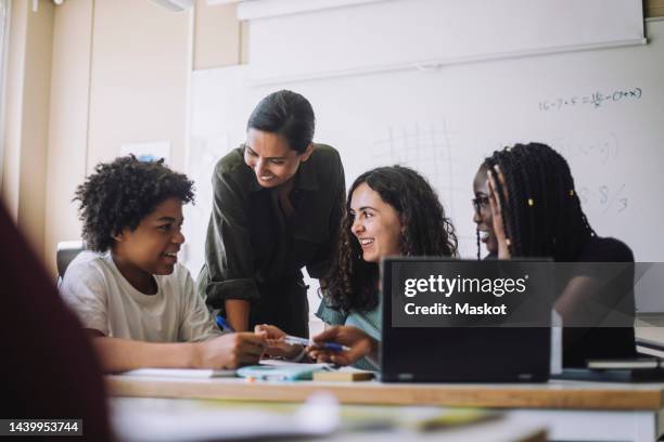 happy female teacher talking with junior high students in classroom at school - student and teacher bildbanksfoton och bilder