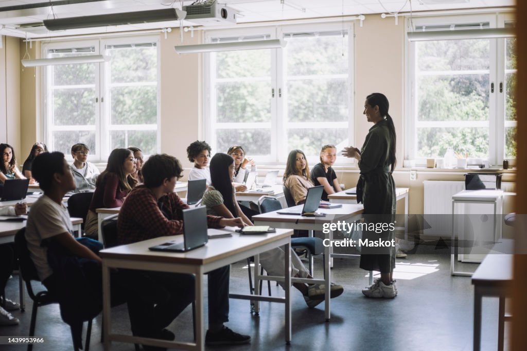 Teacher explaining male and female students in classroom at junior high school