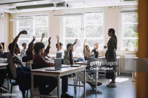 multiracial students raising hands while teacher asking questions in class at school - teachers imagens e fotografias de stock