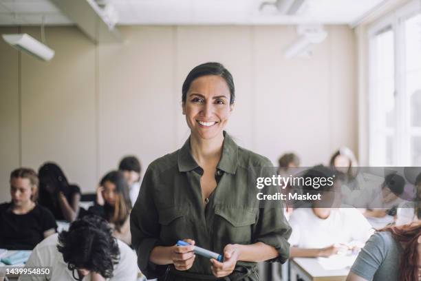 portrait of happy female teacher with students in background at school - arab teen photos et images de collection