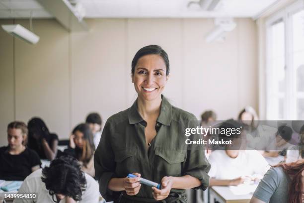 portrait of happy female teacher with students in background at school - teachers stockfoto's en -beelden