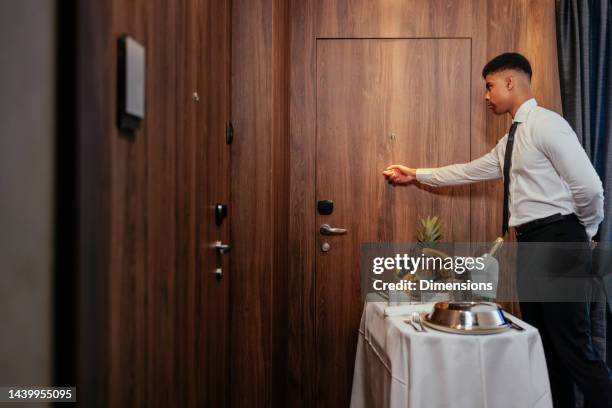 cameriere del servizio in camera che bussa alla porta degli ospiti. - bussare foto e immagini stock