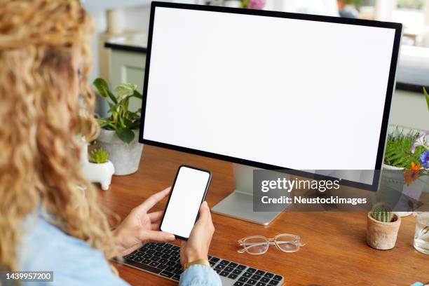businesswoman holding smart phone by desktop pc - desktop computer stock pictures, royalty-free photos & images