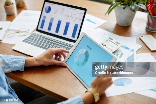businesswoman comparing financial diagrams on tablet pc - plano de atividades imagens e fotografias de stock
