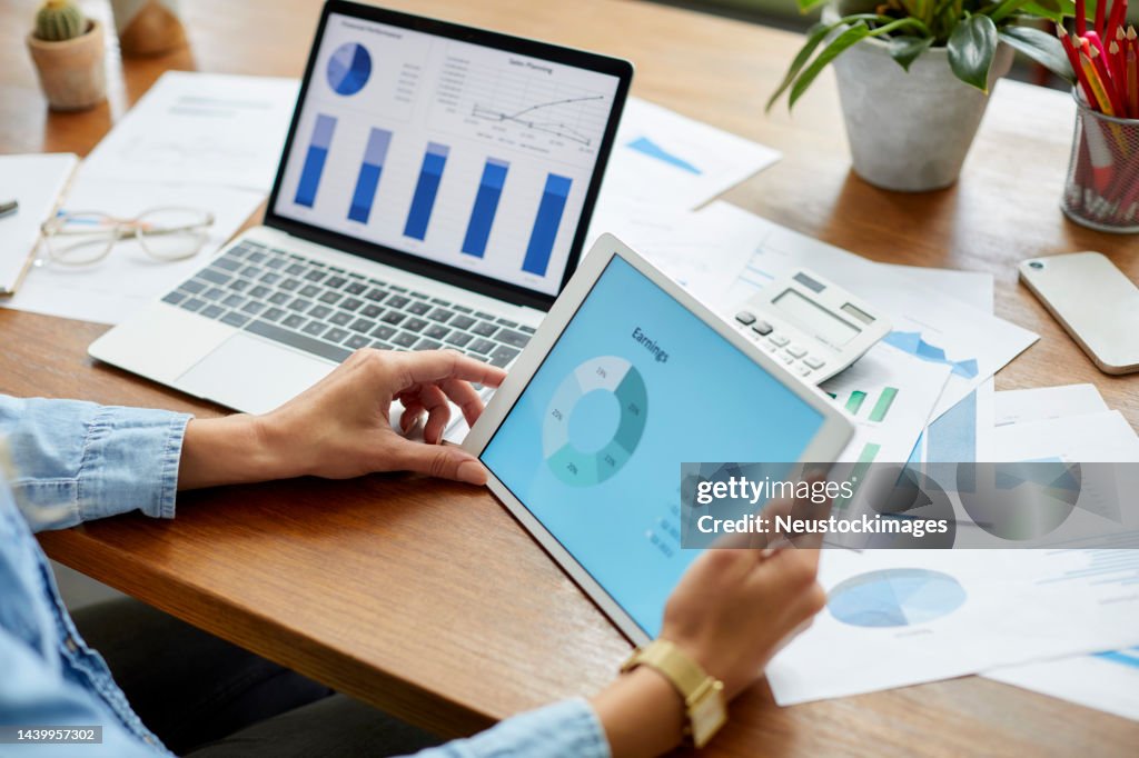 Businesswoman comparing financial diagrams on tablet PC