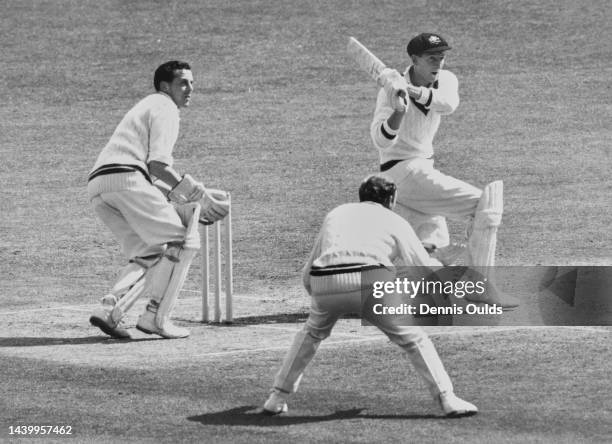 Worcestershire County Cricket Club wicketkeeper Roy Booth looks on from behind the stumps as left handed batsman Bill Lawry of the touring Australian...