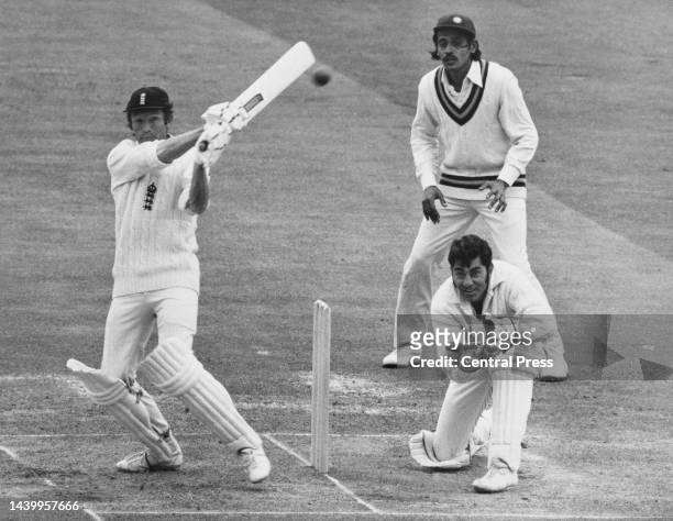 Wicketkeeper Farokh Engineer of India looks on from behind the stumps as Mike Denness of England plays a hook shot off a delivery by Bishan Bedi of...