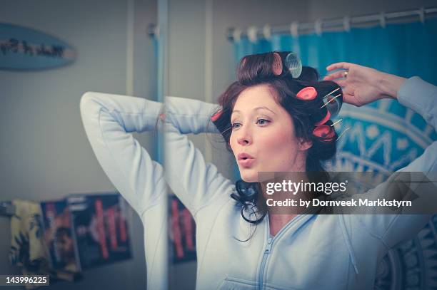 young woman with curlers in bathroom singing - hair curlers stock-fotos und bilder