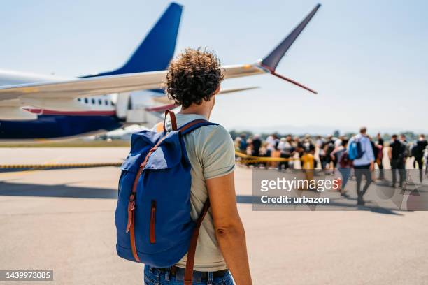 young man boarding an airplane - boarding plane stock pictures, royalty-free photos & images