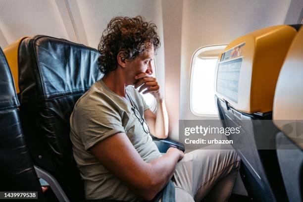 scared male passenger looking out the window of an airplane - phobia imagens e fotografias de stock