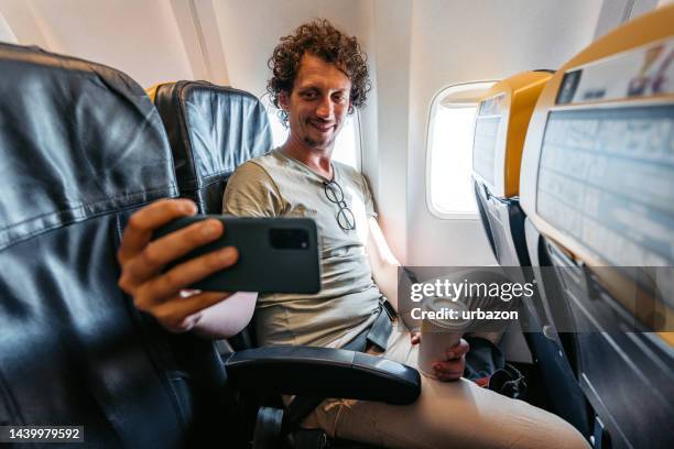 young man taking selfies in an airplane - zelfportret stockfoto's en -beelden